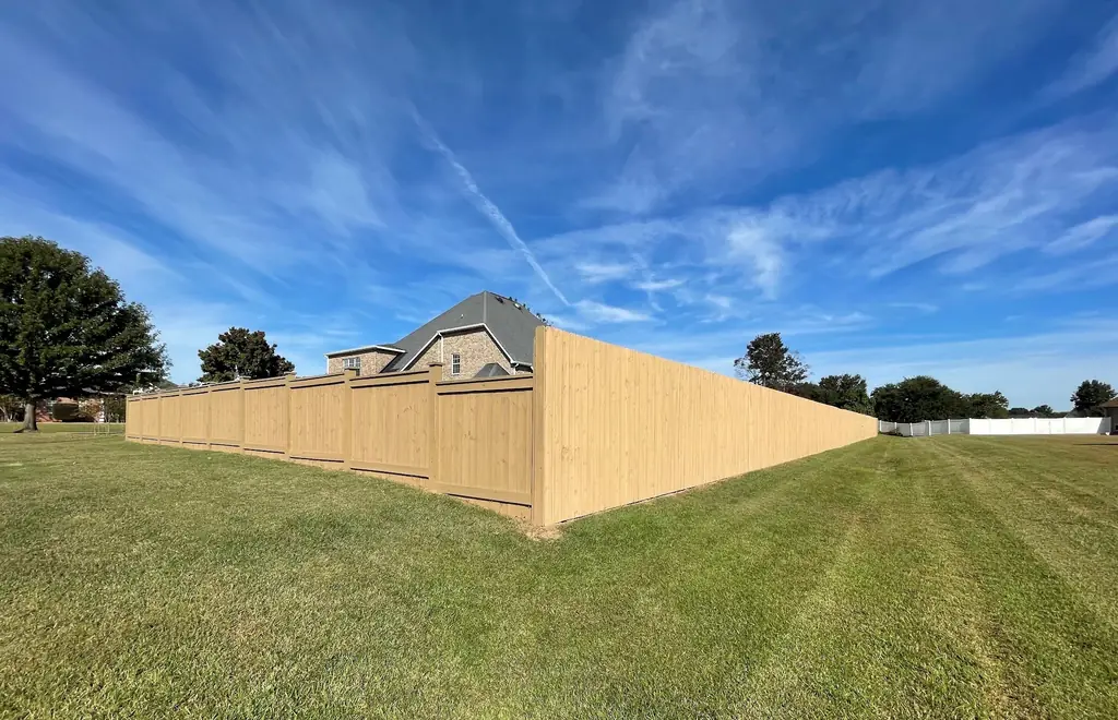 Long tan vinyl privacy fence running in perspective under a deep blue Georgia sky