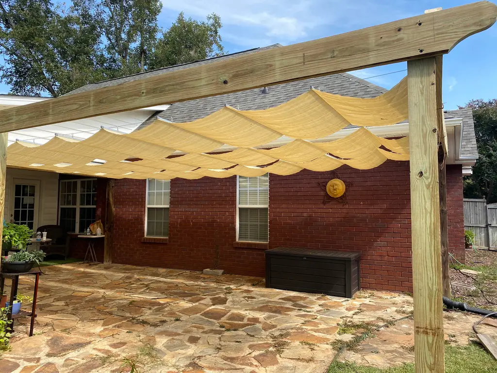 Timber pergola with a fitted tan shade canopy over a flagstone patio
