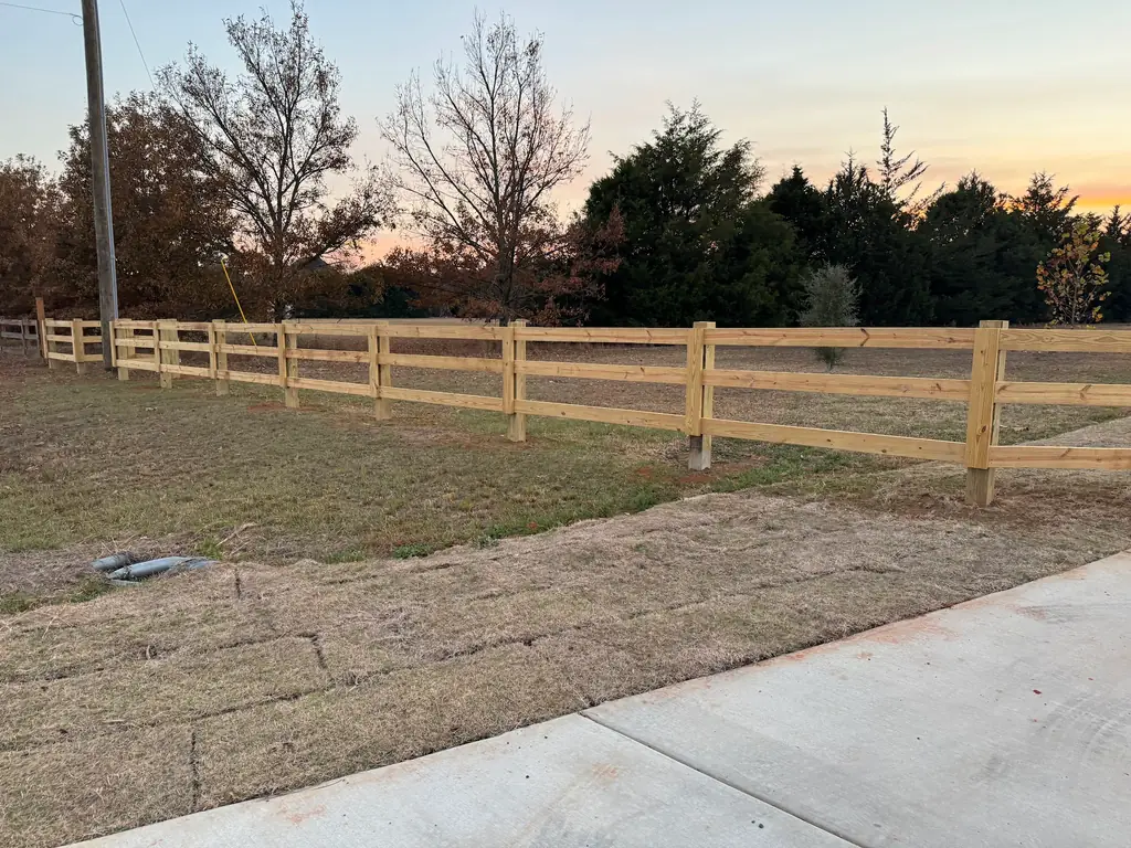 Three rail ranch fence running into the treeline at golden hour in middle Georgia